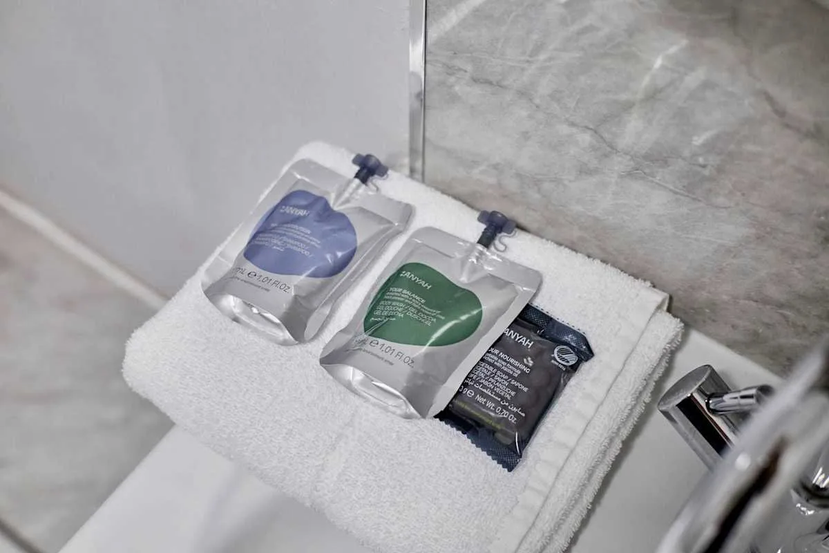 Bathroom toiletries are arranged on a folded white towel beside the sink.