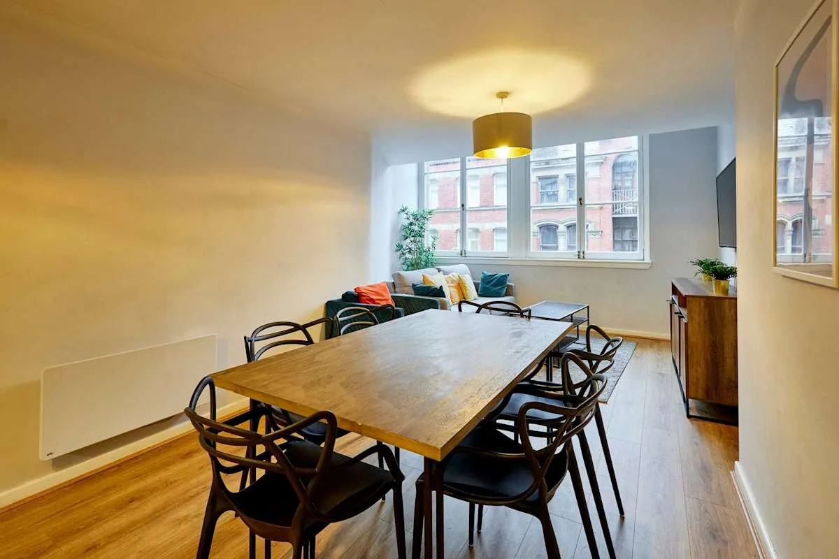 A dining area with a wooden table and seating beside a living area.