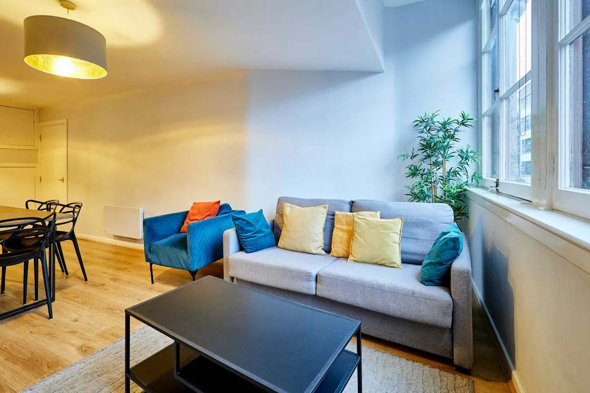 Living room with a sofa, colorful cushions, and a large window.