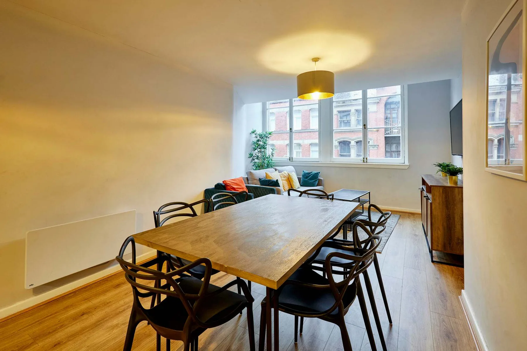 A dining area with a wooden table and seating beside large windows.