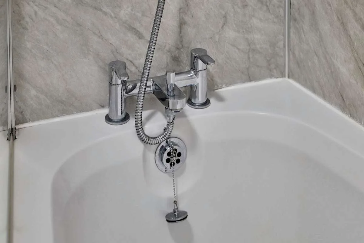 A bathtub with wall-mounted taps and a handheld shower.