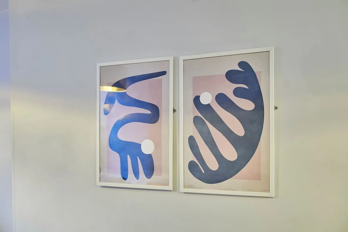 Two framed abstract prints hang on a light-colored wall.