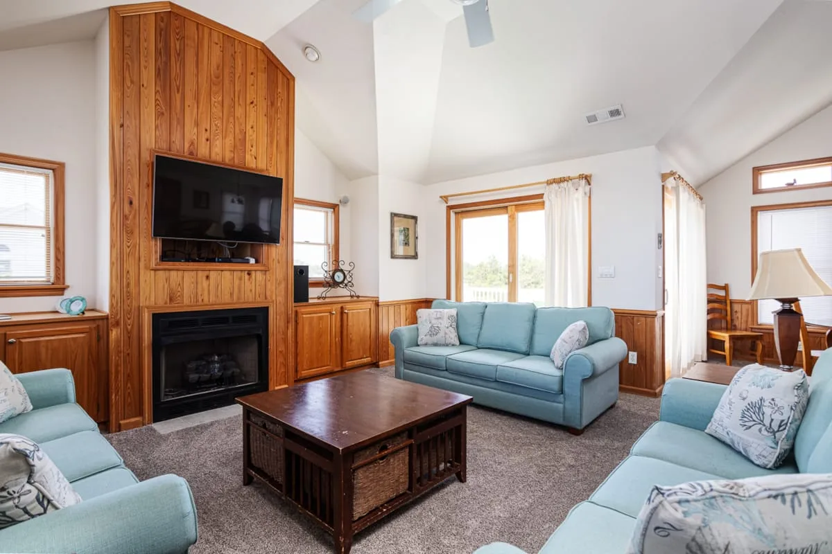 Una sala de estar con asientos azules y un mueble de entretenimiento de madera.