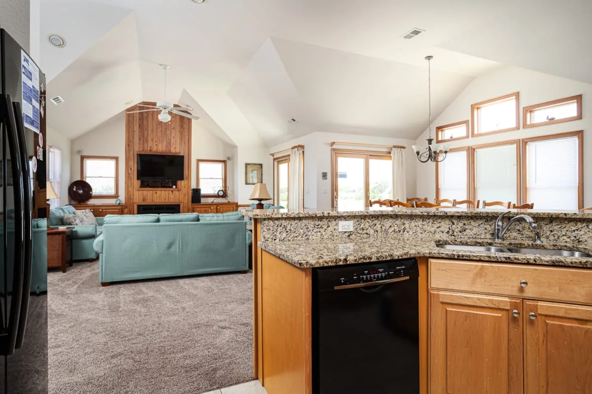Sala de estar y cocina de concepto abierto, con una isla de granito y asientos.