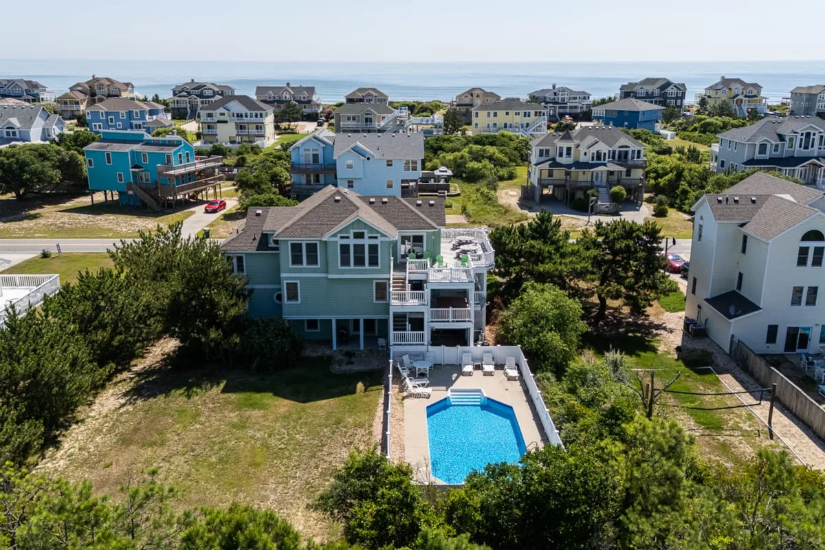 Aerial view of coastal houses, with a swimming pool in the foreground.