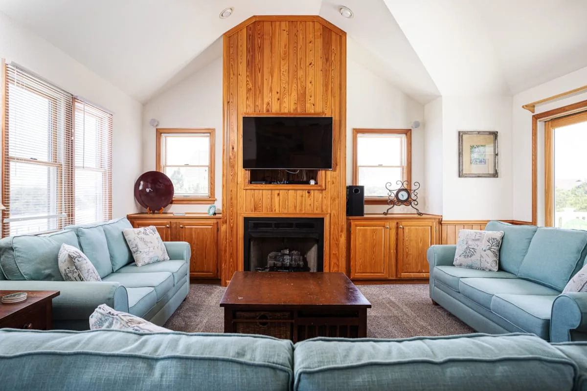 A living room with blue seating arranged around a central wooden entertainment unit.