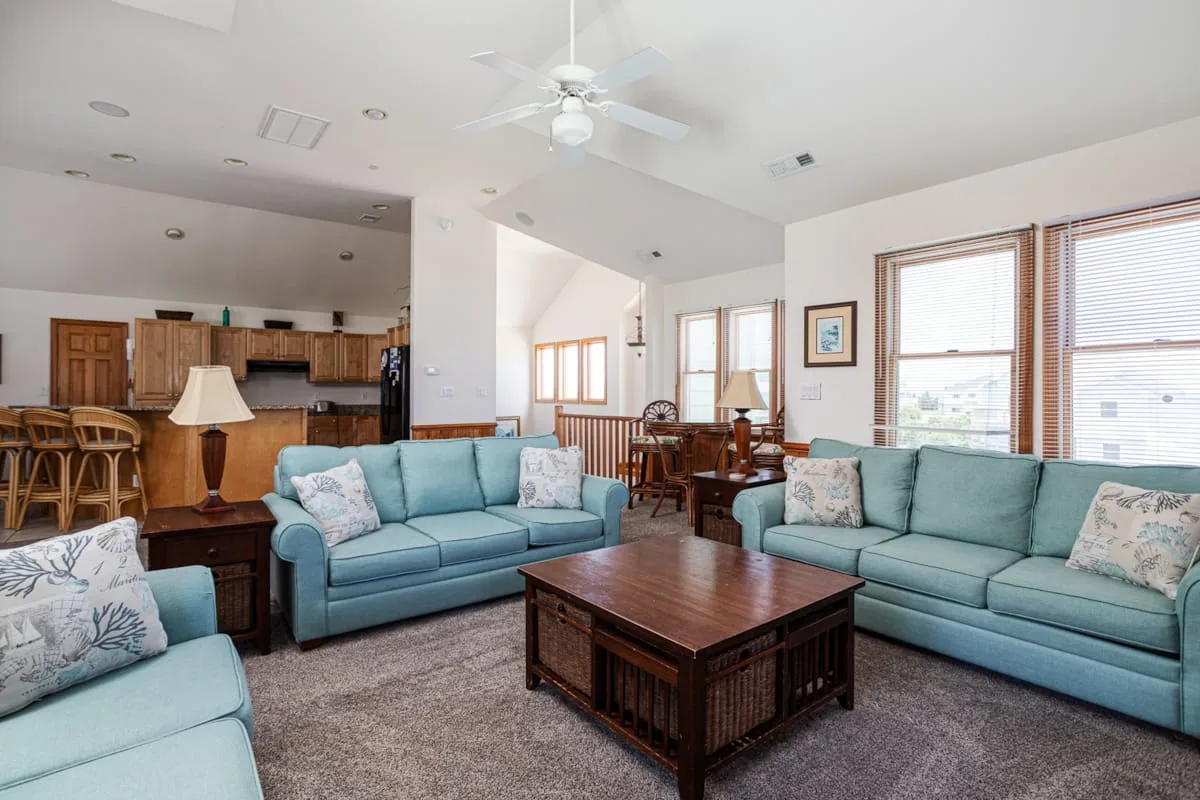 A living room with teal seating and a wooden coffee table.