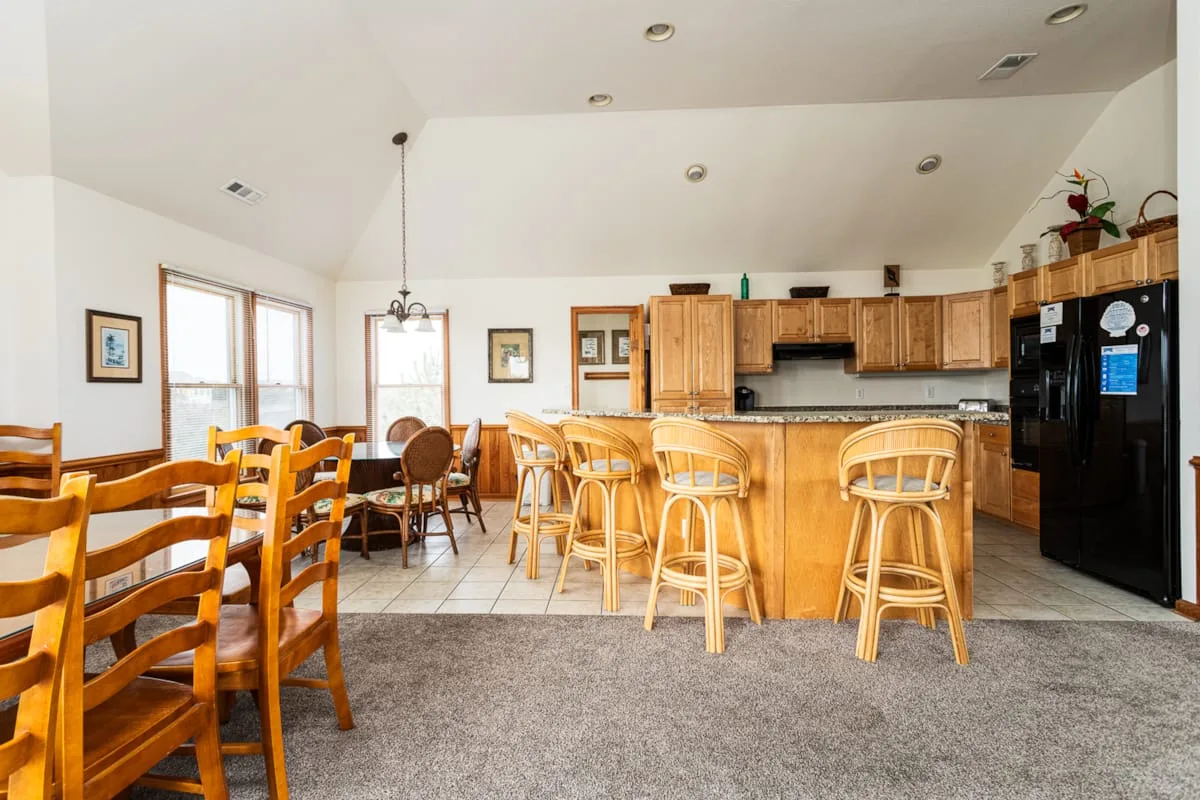 Una cocina abierta con zona de comedor, barra y asientos de madera.