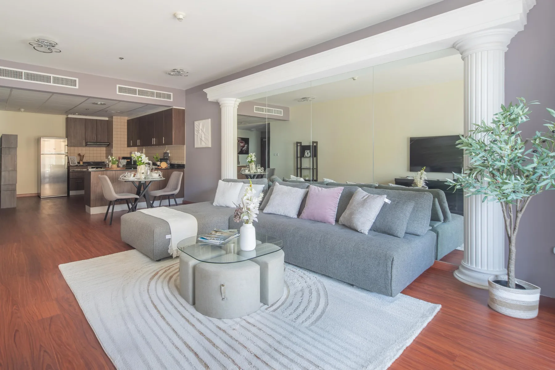 Sala y comedor de concepto abierto con un sofá seccional gris y una mesa de centro de vidrio.