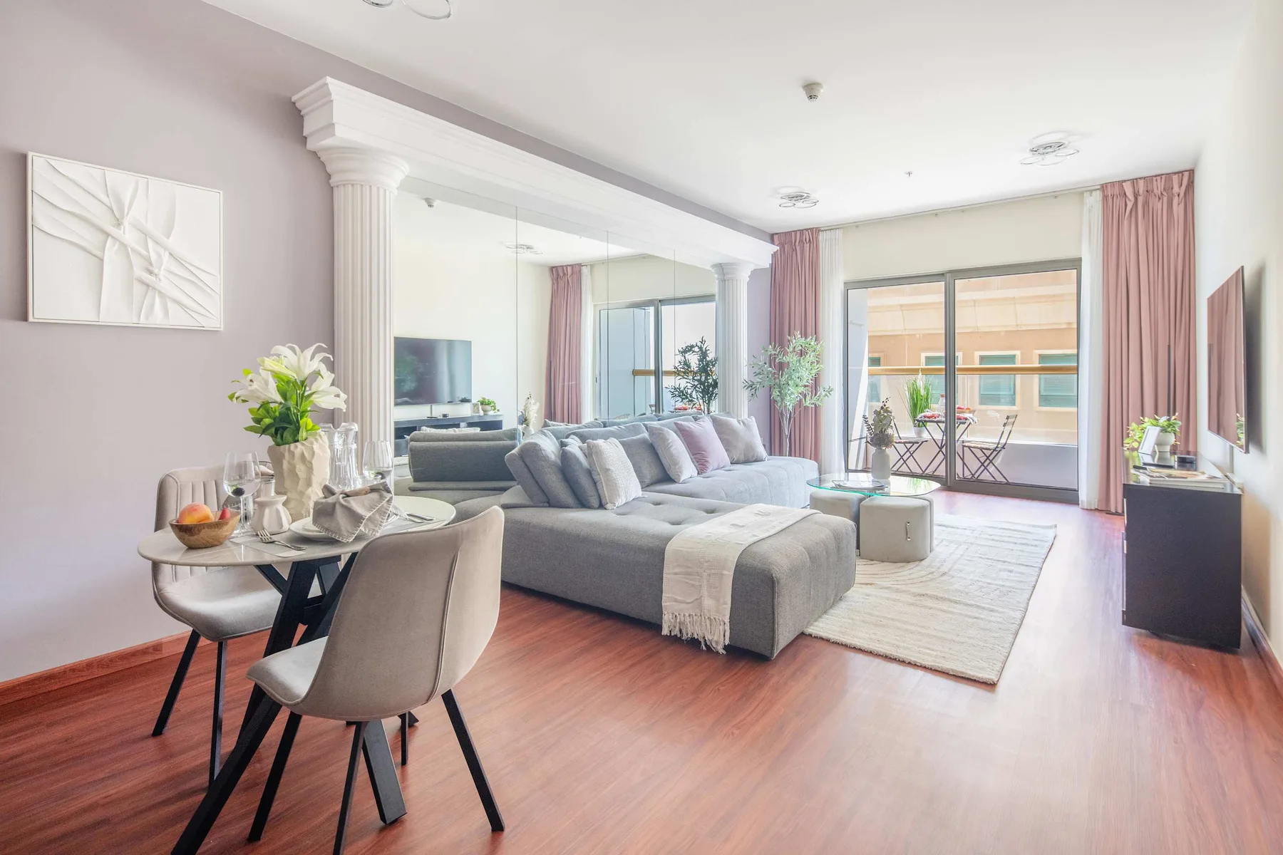 Una sala luminosa con sofá seccional, mesa de comedor y grandes ventanales.