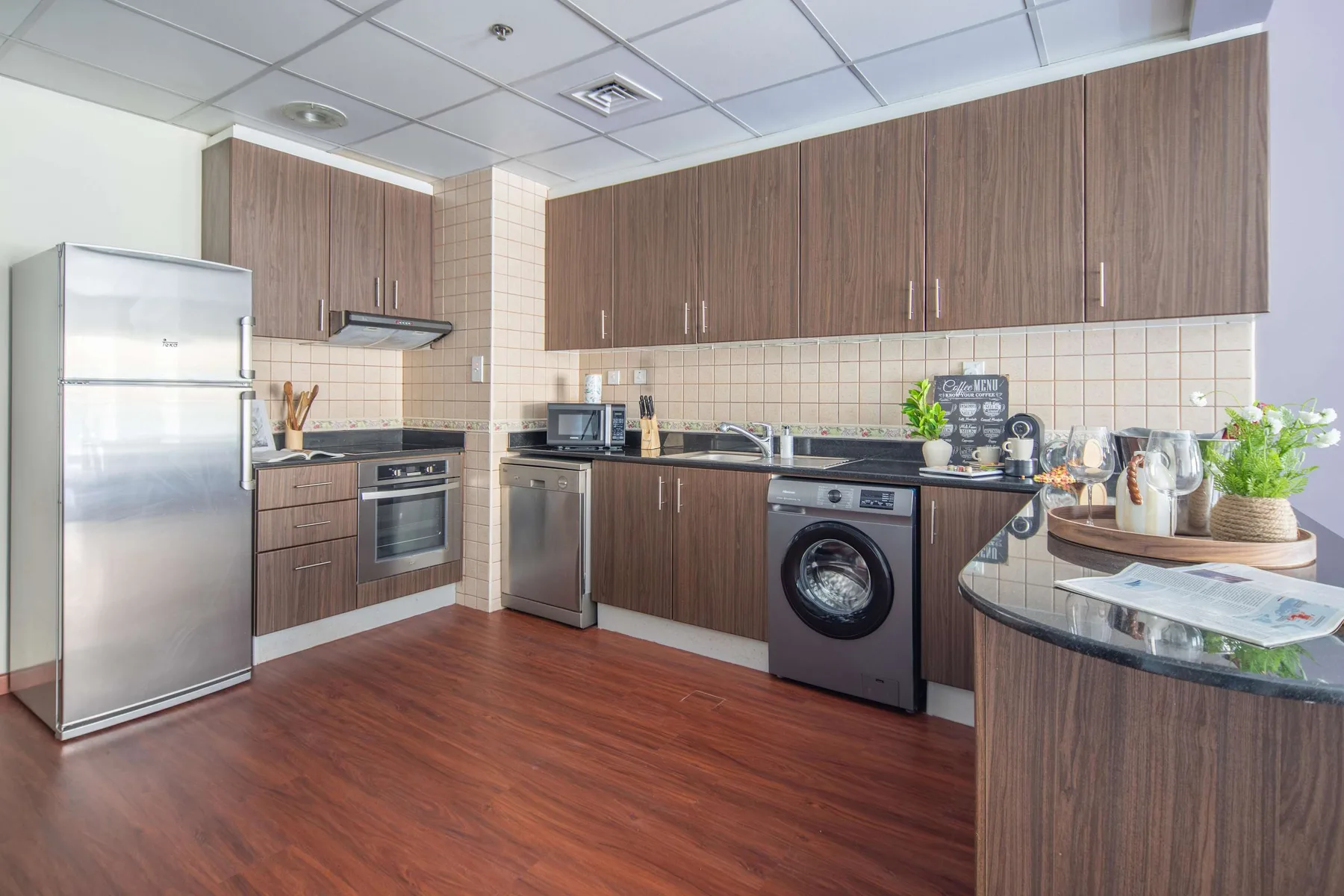 Una cocina amplia con gabinetes de madera, electrodomésticos de acero inoxidable y una encimera central.
