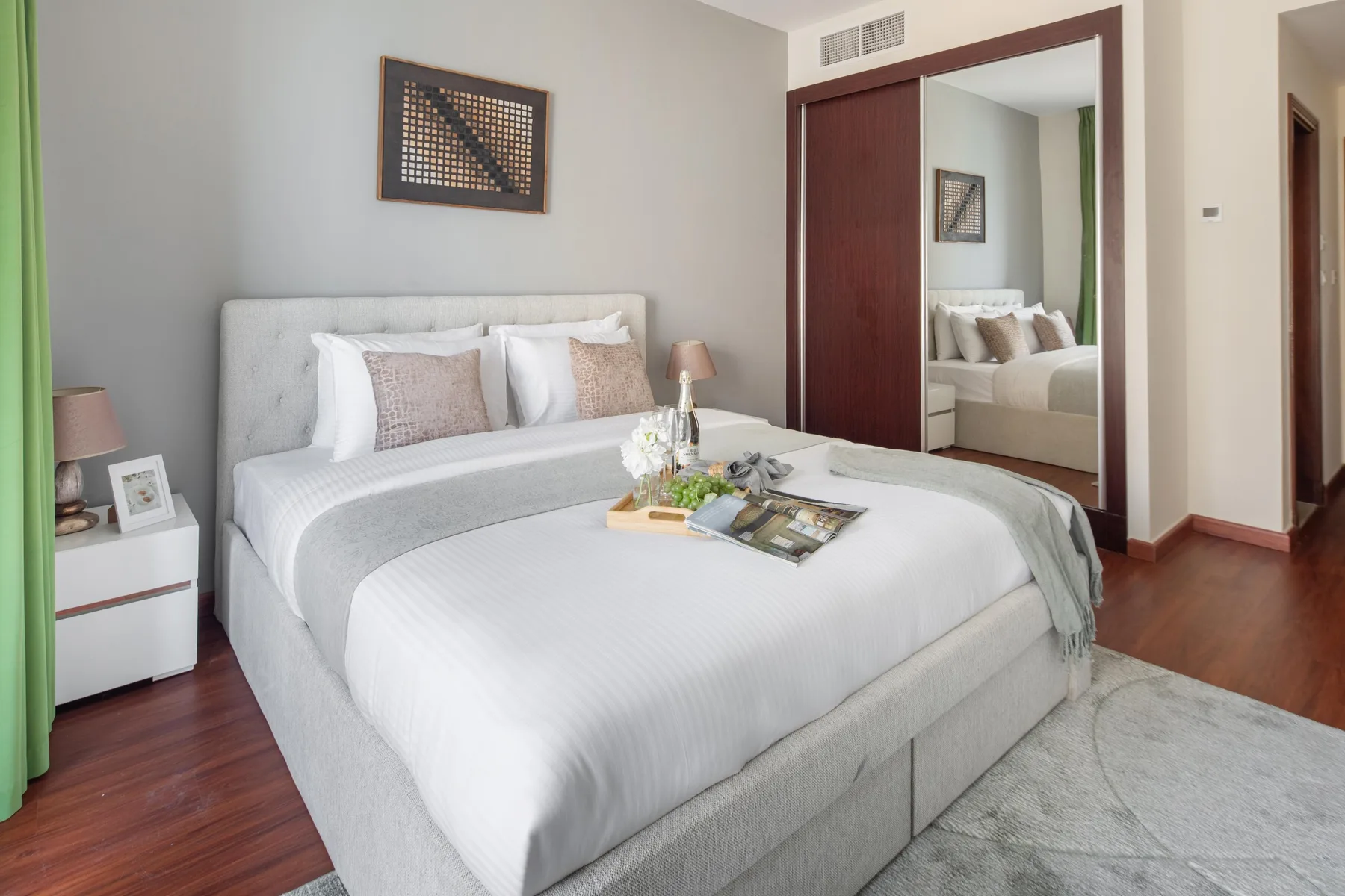 Un dormitorio con una cama bien tendida y un armario con espejo.
