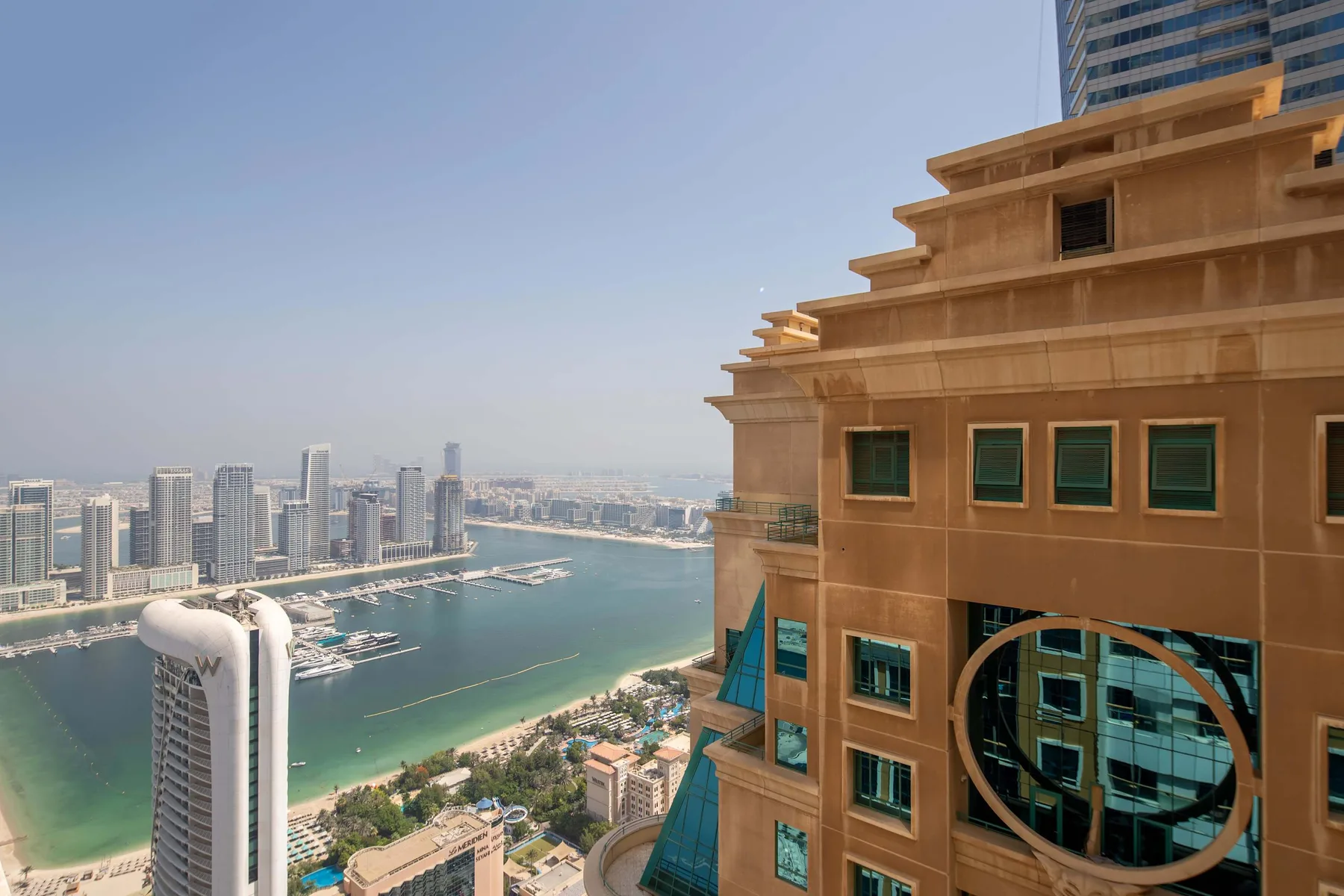 El horizonte de una ciudad costera domina una marina junto a un gran edificio beige.