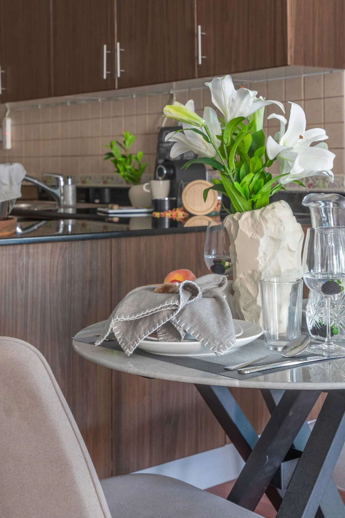 Una mesa de comedor con flores blancas está frente a una cocina compacta.