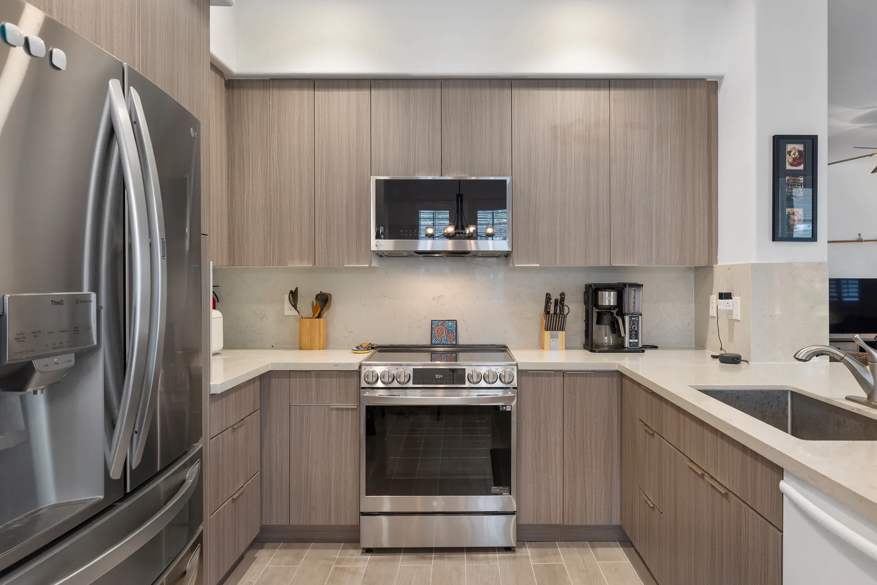 Una cocina moderna con gabinetes de madera, electrodomésticos de acero inoxidable y una encimera clara.