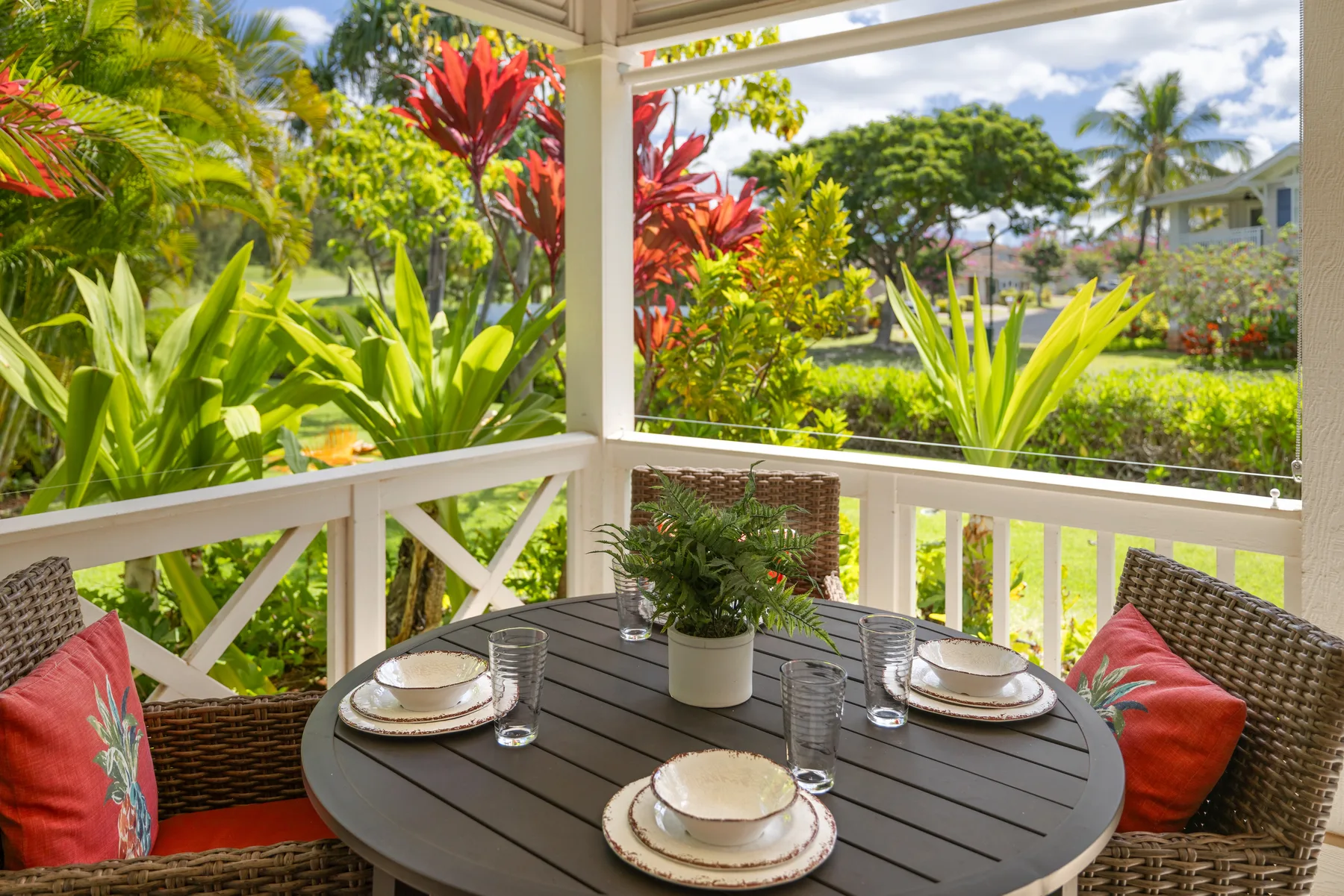 Una zona de comedor al aire libre amueblada da a un exuberante jardín tropical.