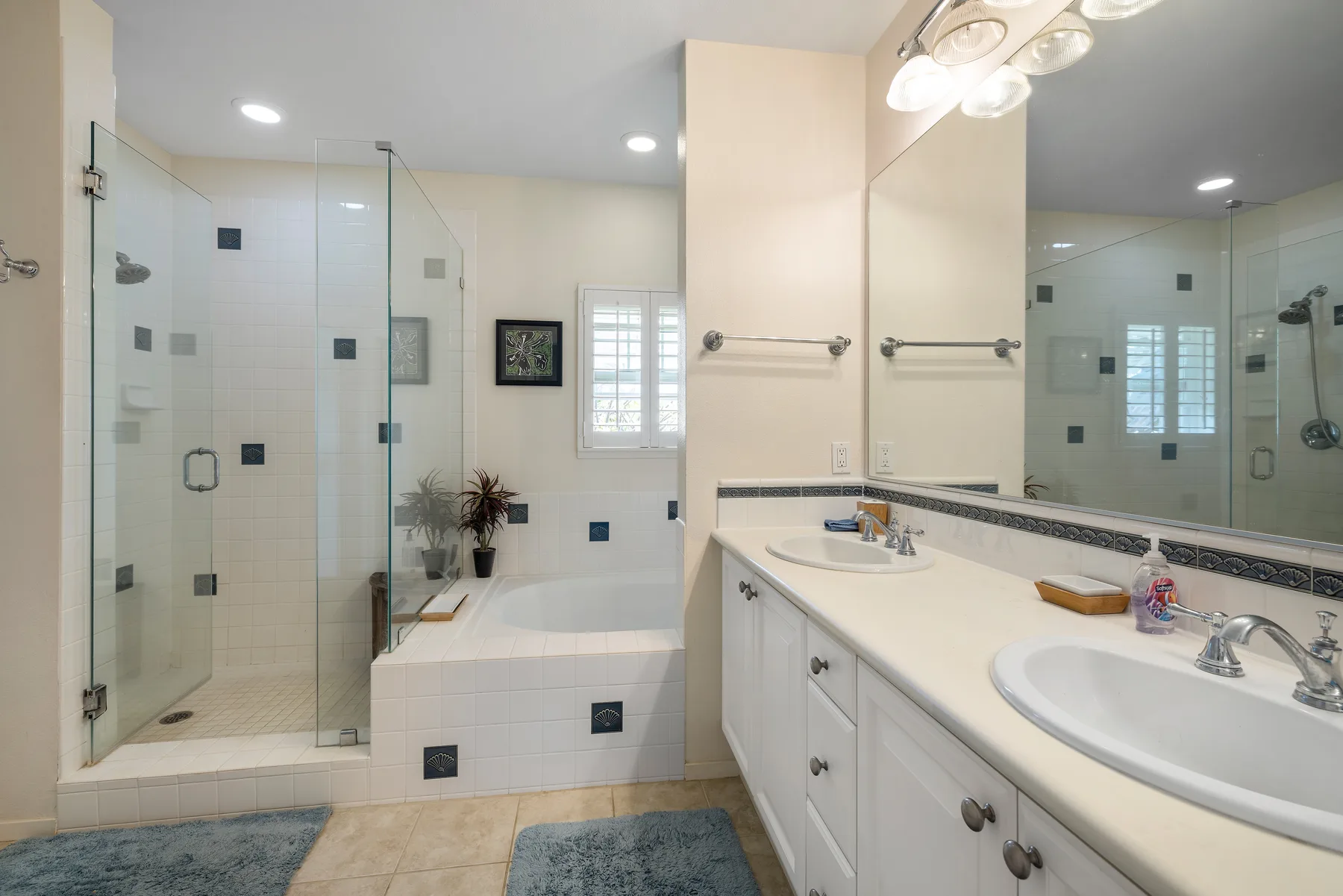 Baño luminoso con ducha de vidrio, bañera y un largo tocador.