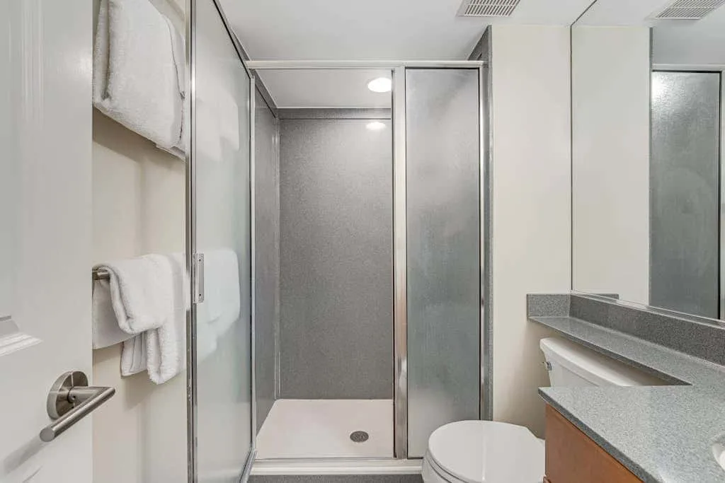 A bathroom with a glass shower, toilet, and countertop.