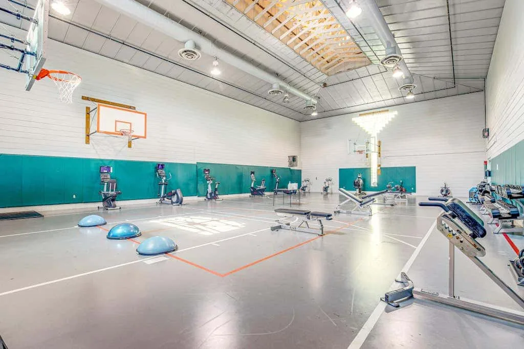 An indoor gym with basketball hoops, exercise equipment, and court markings.