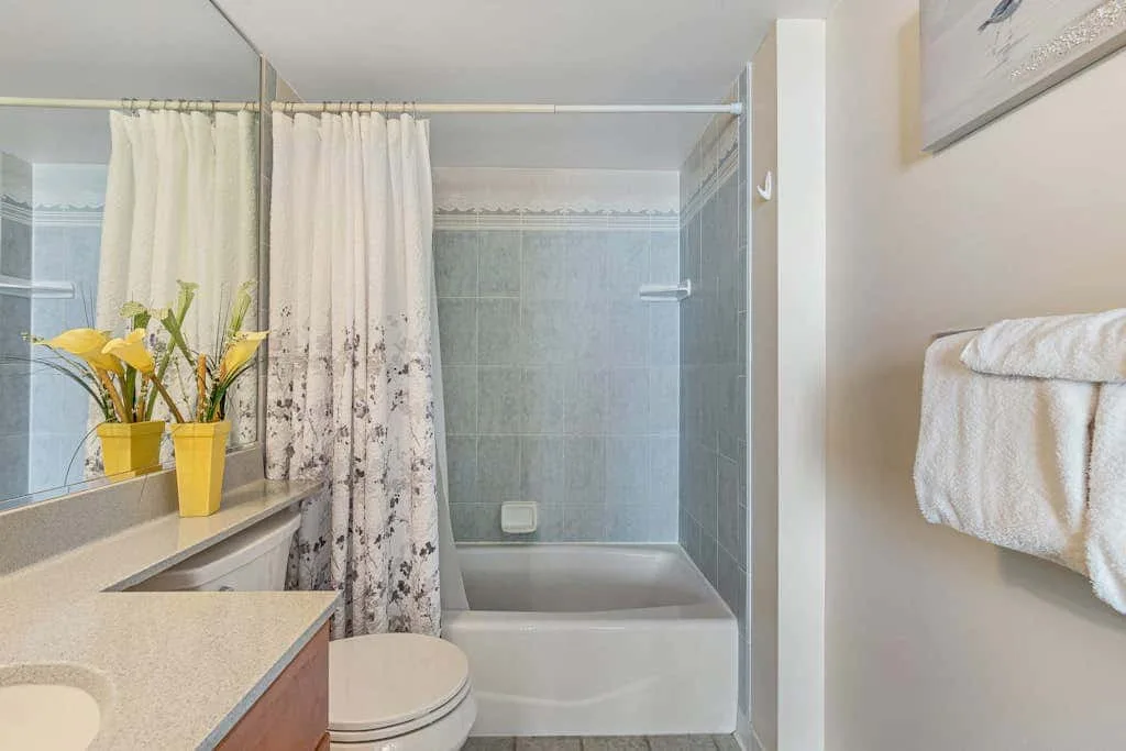 A bathroom with a bathtub, shower curtain, and sink.