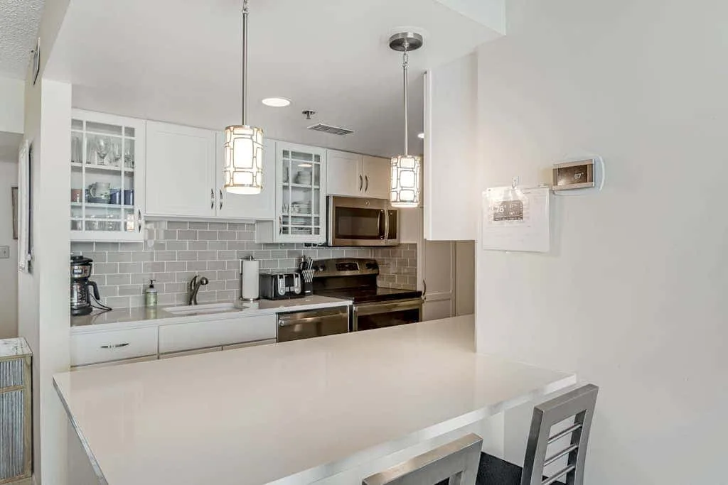 A bright kitchen with white cabinets and a broad counter.