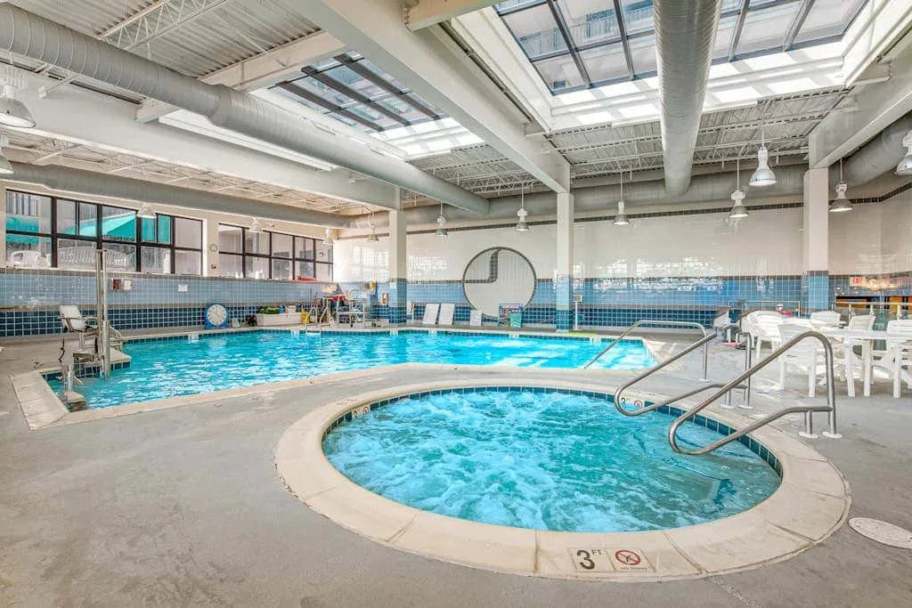 An indoor swimming pool with a round bubbling spa in the foreground.