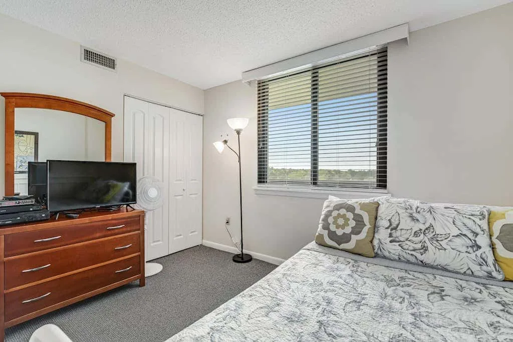 A bedroom with a bed, dresser, and window overlooking the landscape.