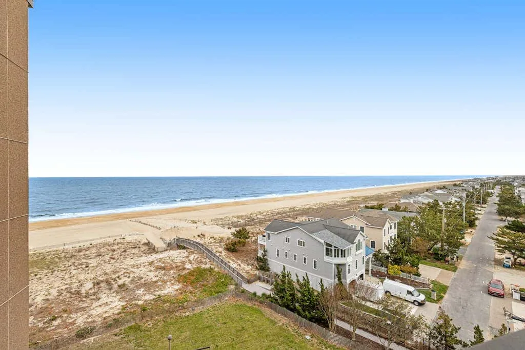 A coastal neighborhood beside a sandy beach, viewed from above.