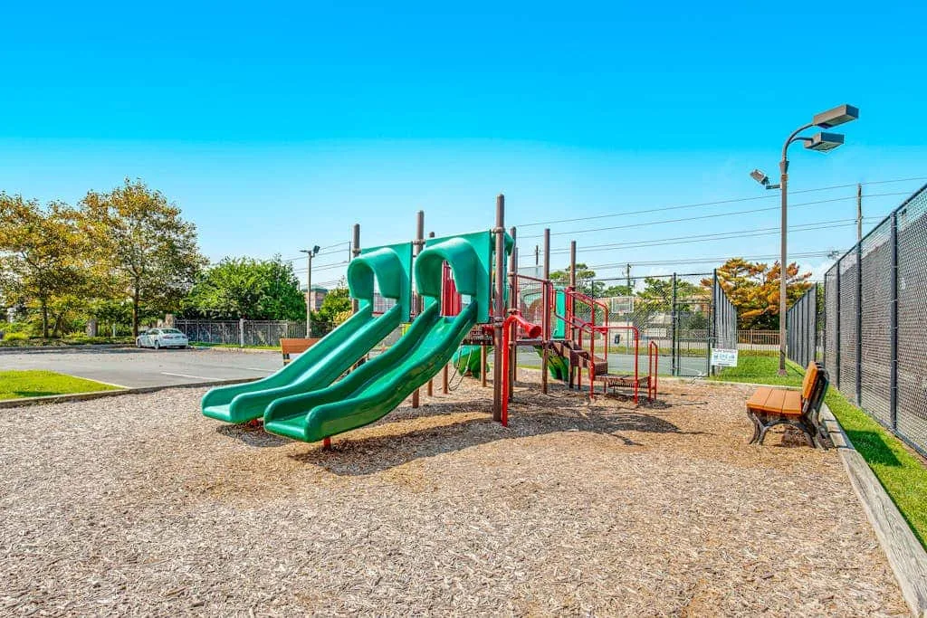 An outdoor playground with green slides and play equipment.
