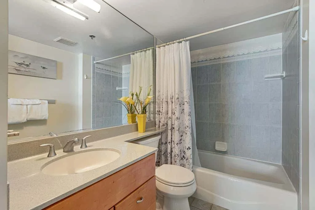 A bathroom with a bathtub, shower curtain, and vanity.