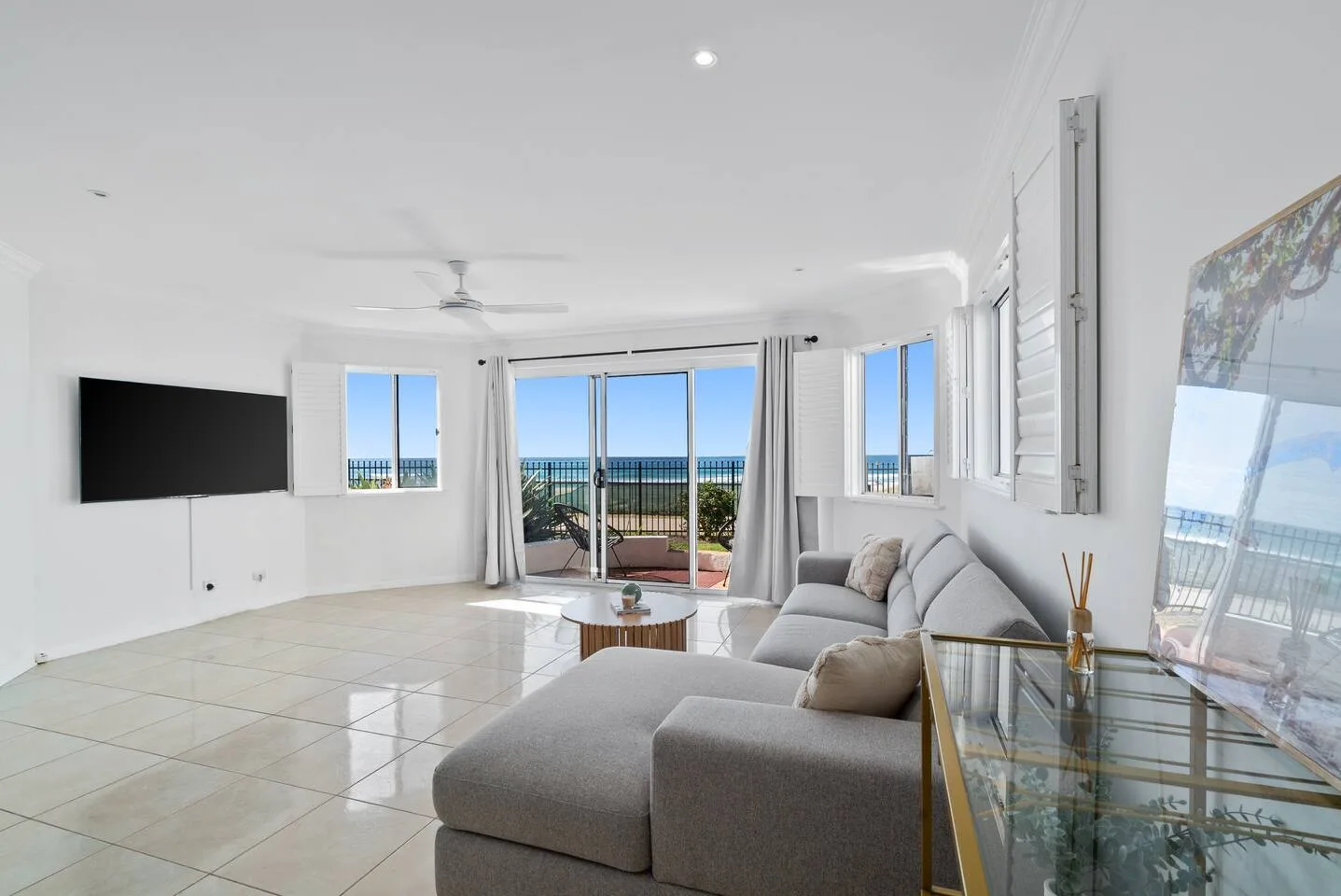 Una sala luminosa con un sofá seccional y puertas corredizas de vidrio con vista al agua.