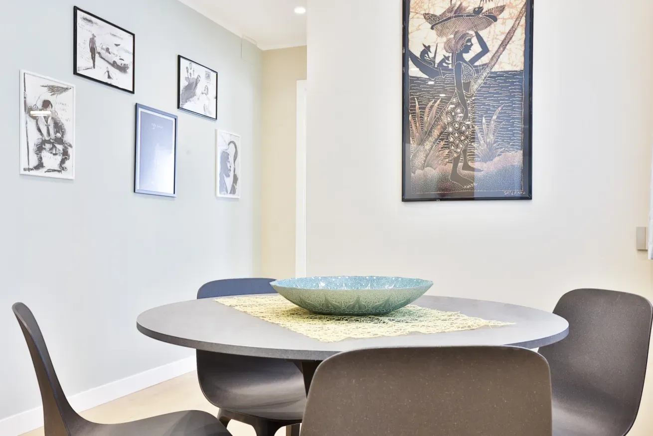 A dining area with a round table, seating, and framed artwork on the walls.