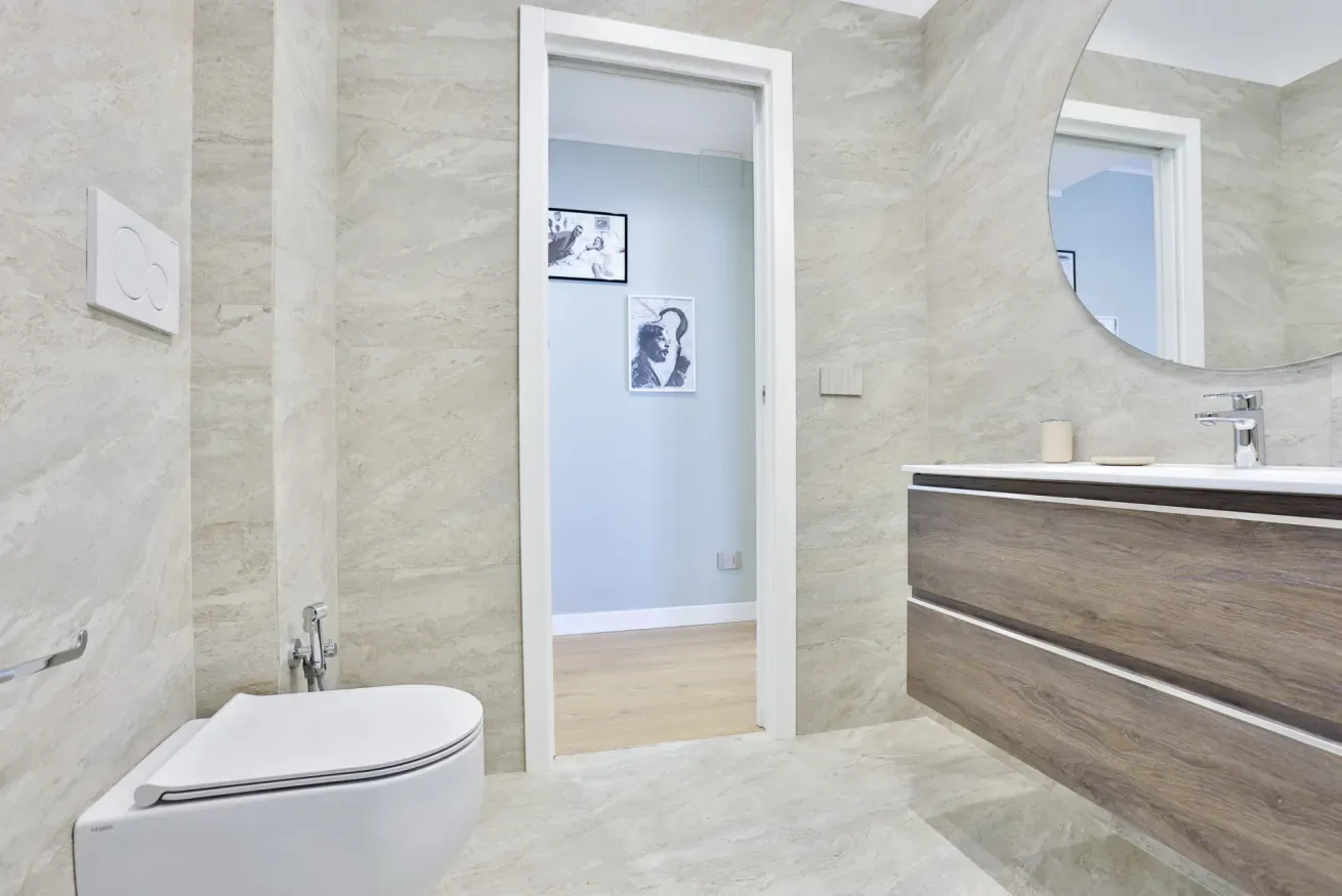 A modern bathroom with a wall-mounted sink cabinet and a doorway to an adjoining room.