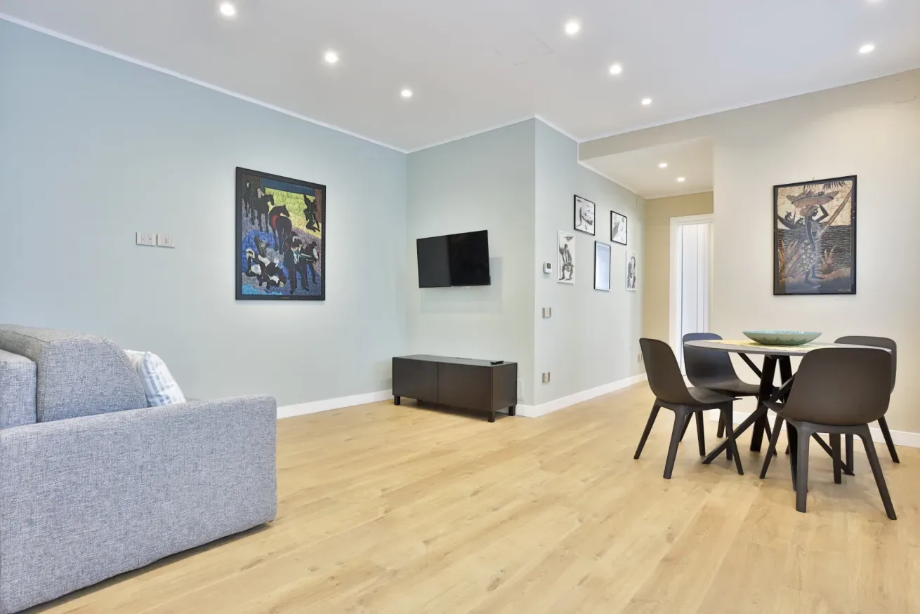 Living and dining area with seating, a table, and wall-mounted television.