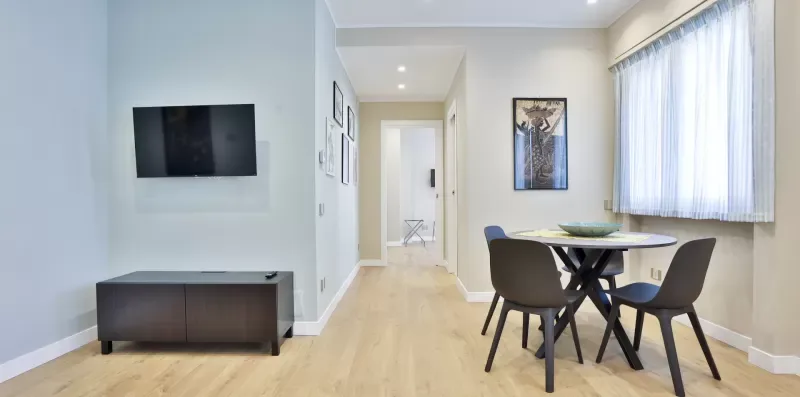 A bright dining area with a table and seating beside a large window.