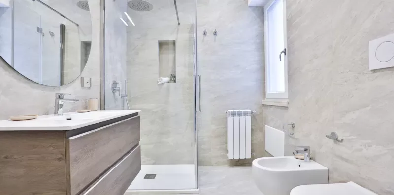 A bright bathroom with a glass shower and a wood-fronted vanity.