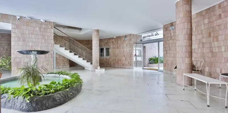 A spacious tiled lobby with a staircase and indoor plants.