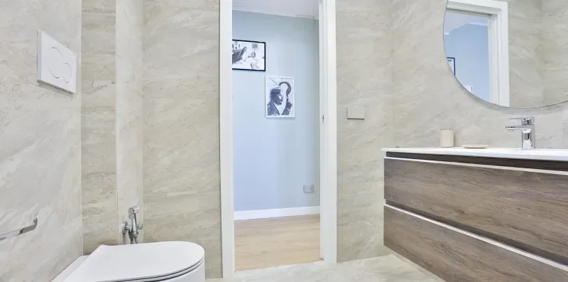 A bathroom with a vanity, mirror, and doorway to an adjacent room.