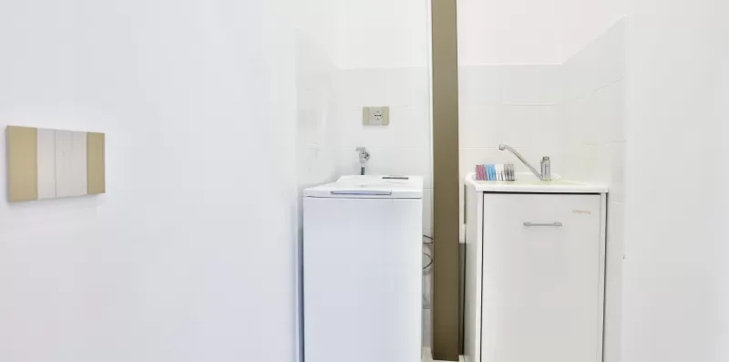 A bright bathroom with a sink and a washing machine.
