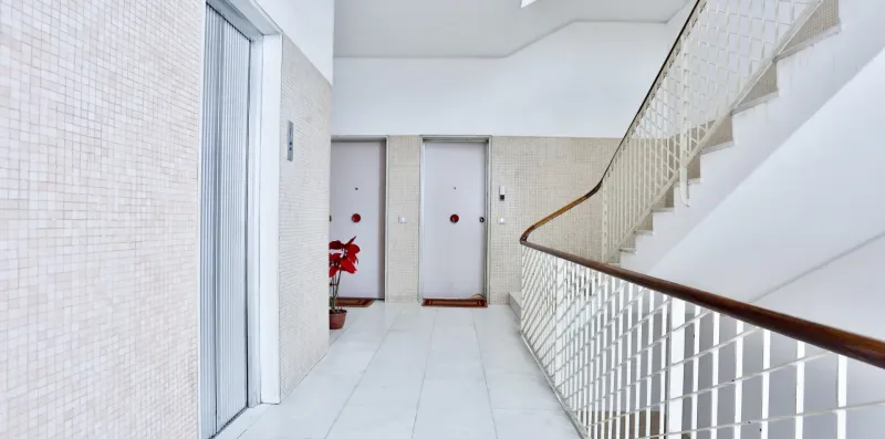 A bright indoor hallway opens onto a staircase with metal railings.