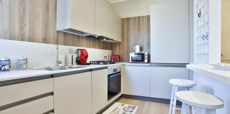 A modern kitchen with pale cabinets, a countertop, and a stovetop.