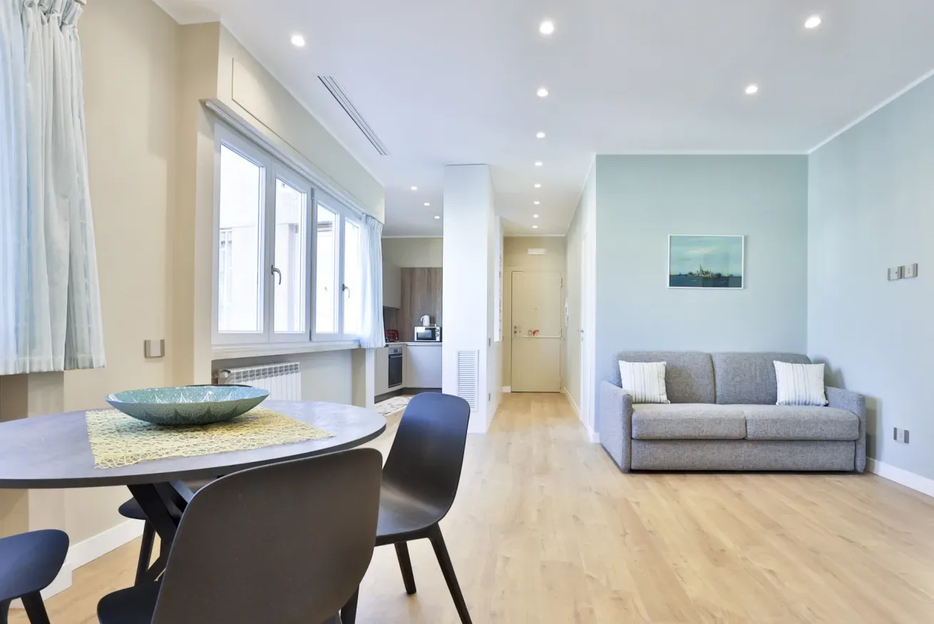 A bright living and dining area with a table, seating, and a sofa.