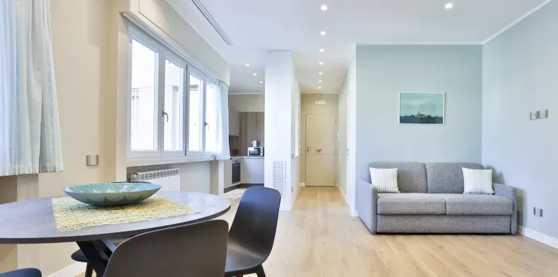 A bright living room with gray seating and large windows.