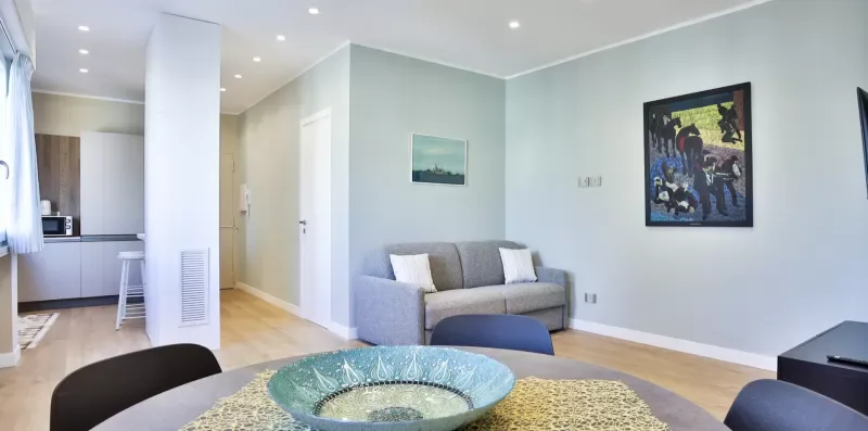 A bright living area with seating, a dining table, and artwork on the wall.