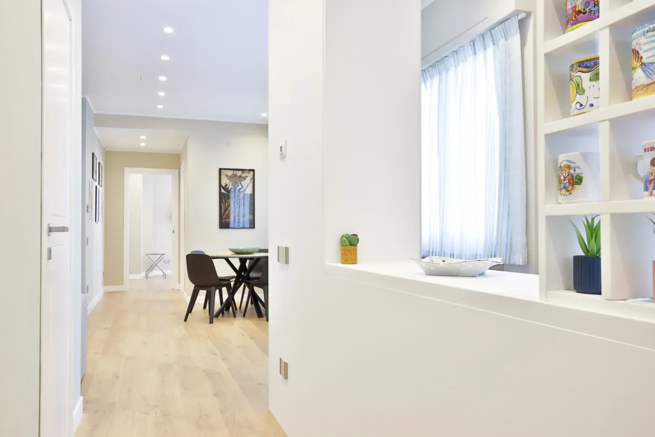 A bright dining area with a table and chairs beside a window and built-in shelves.
