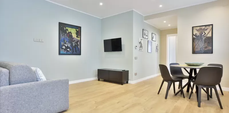 A bright living and dining area with seating, a table, and framed artwork.