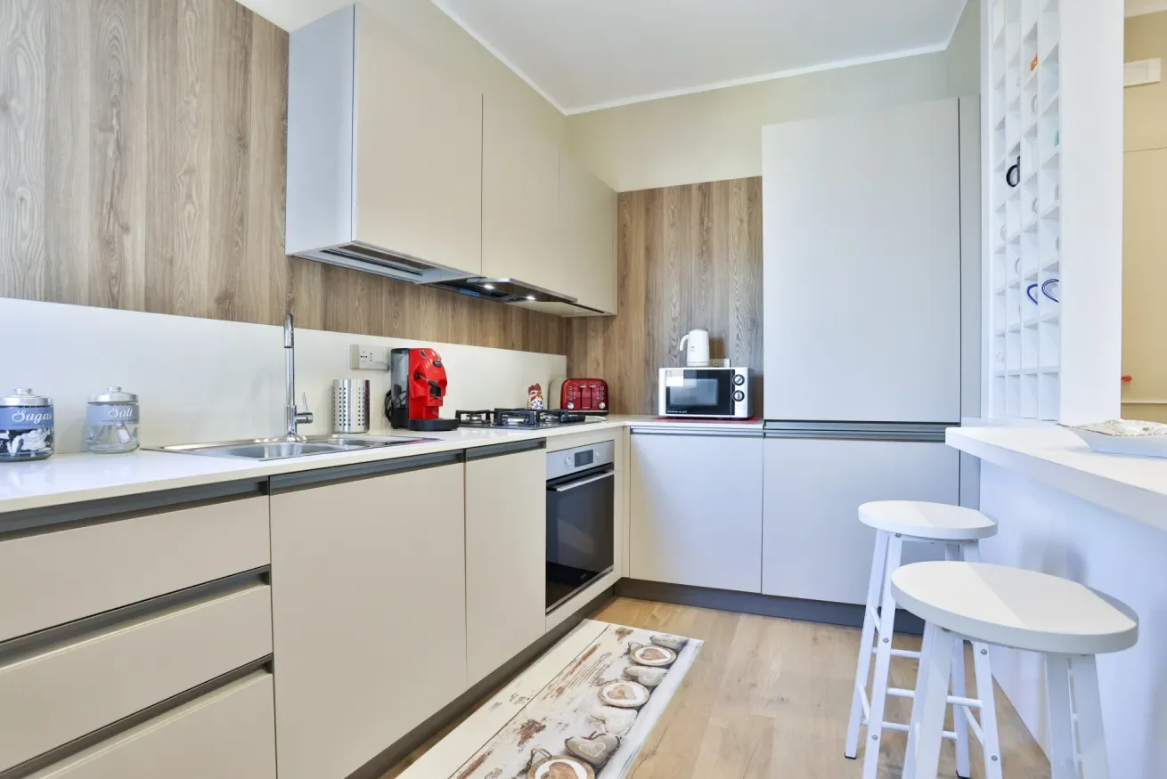 A modern kitchen with light cabinetry, a countertop, and two stools.