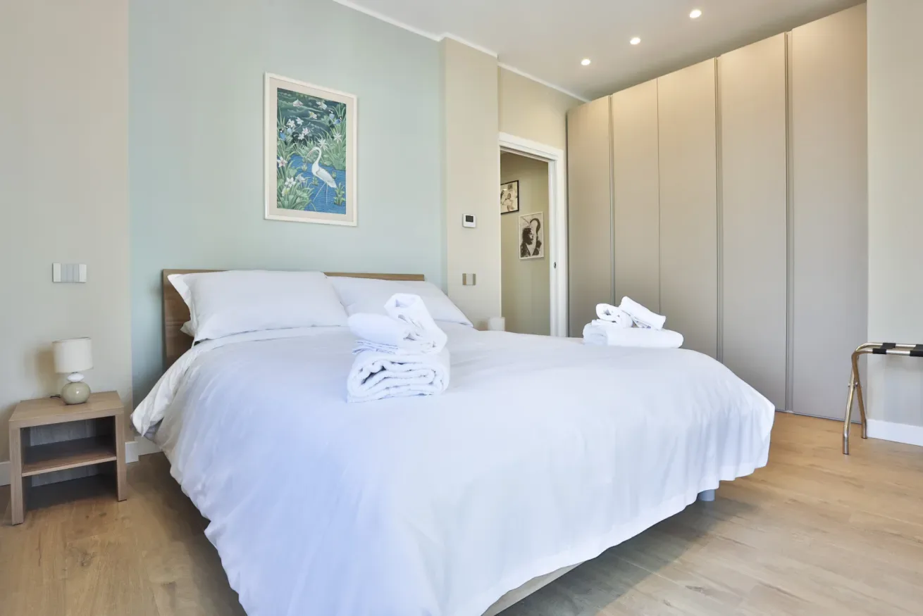 A bright bedroom with a neatly made bed and built-in wardrobes.