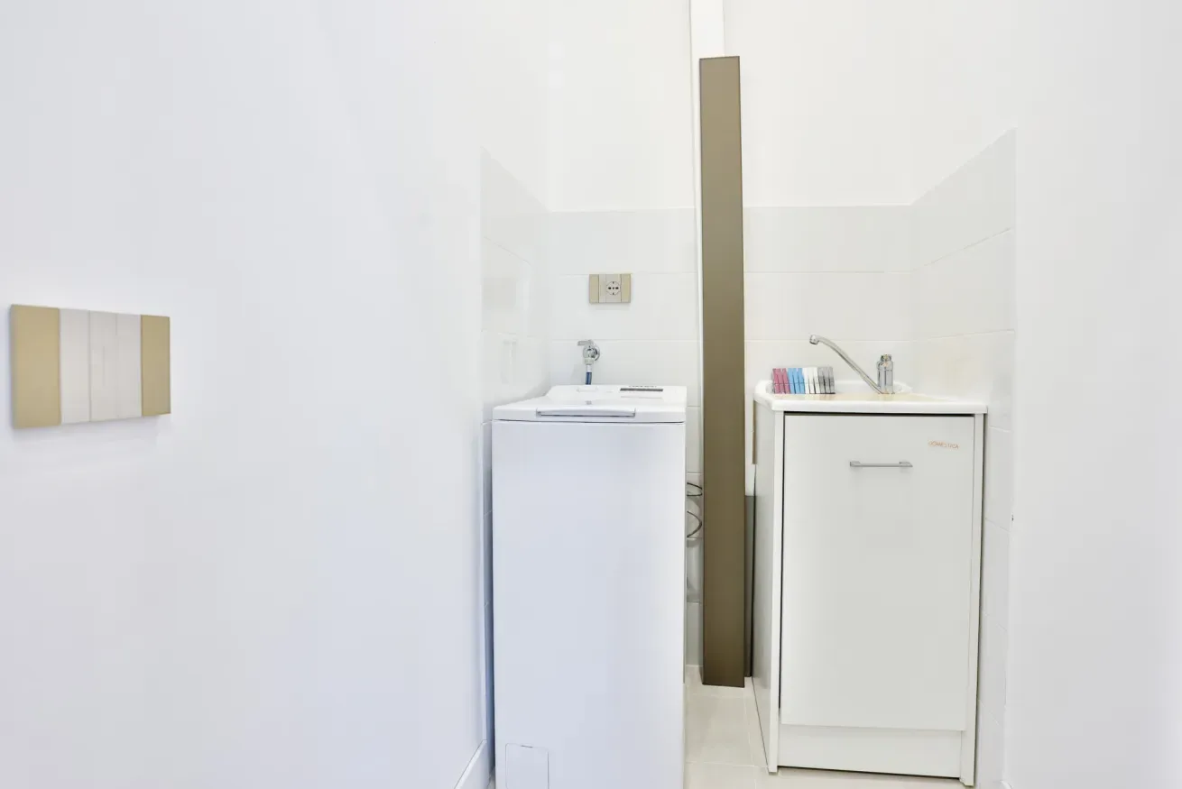 A laundry area with a washing machine beside a sink and cabinet.