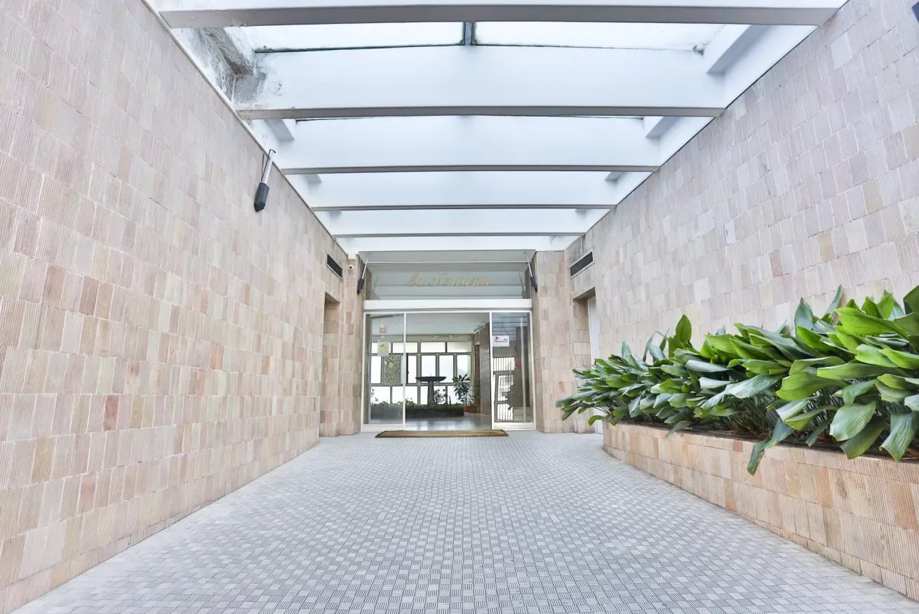 A covered entry passage leads to glass doors, with a long planter along one side.